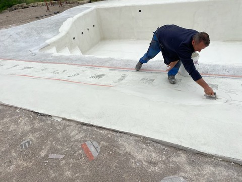 Applying Poseidon to the pool deck with a trowel